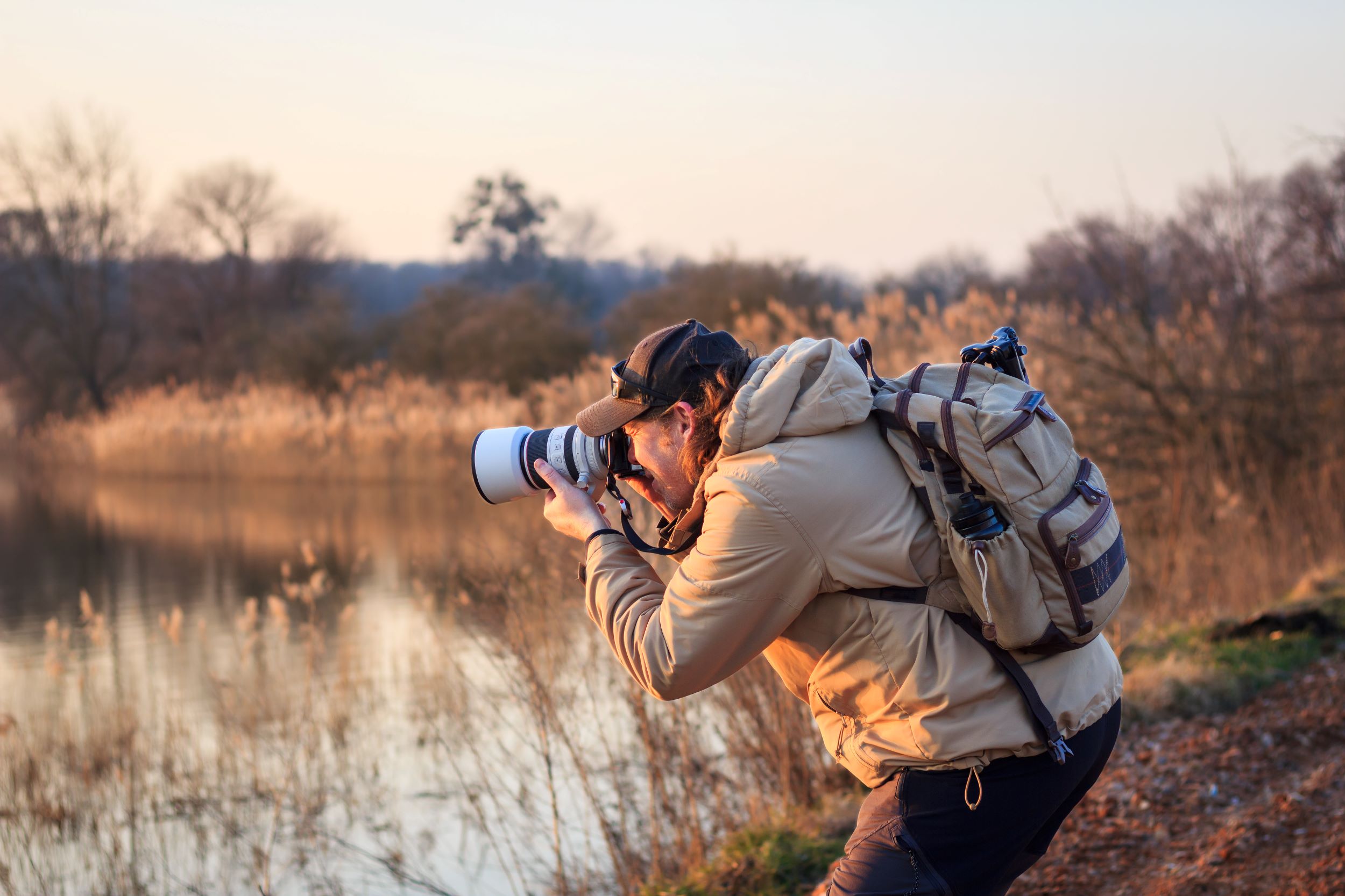 A birdwatcher photographing a bird at sunset.