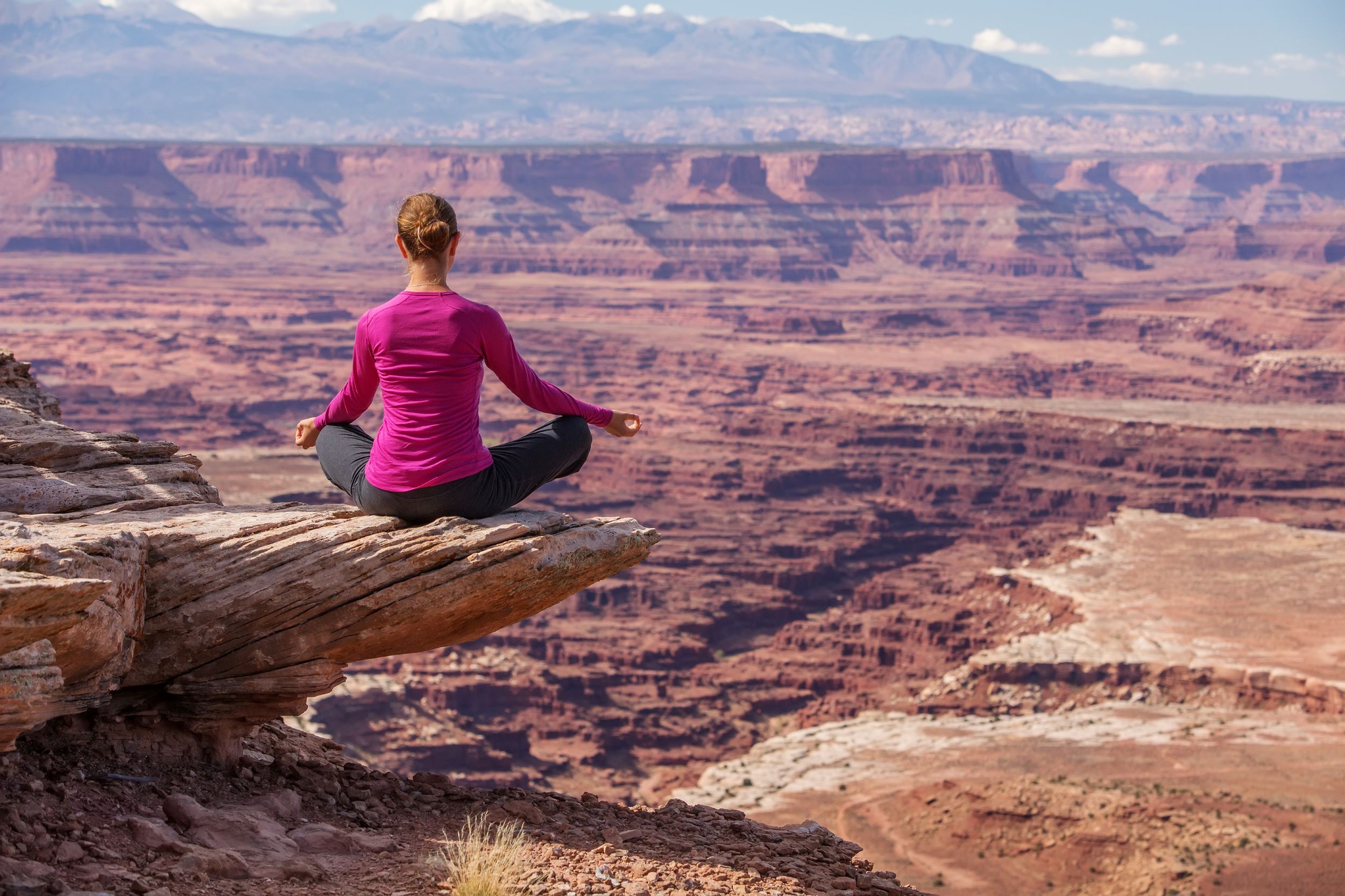 A woman doing yoga on the edge of a canyon.