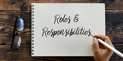 Writing in a notebook, roles and responsibilities.